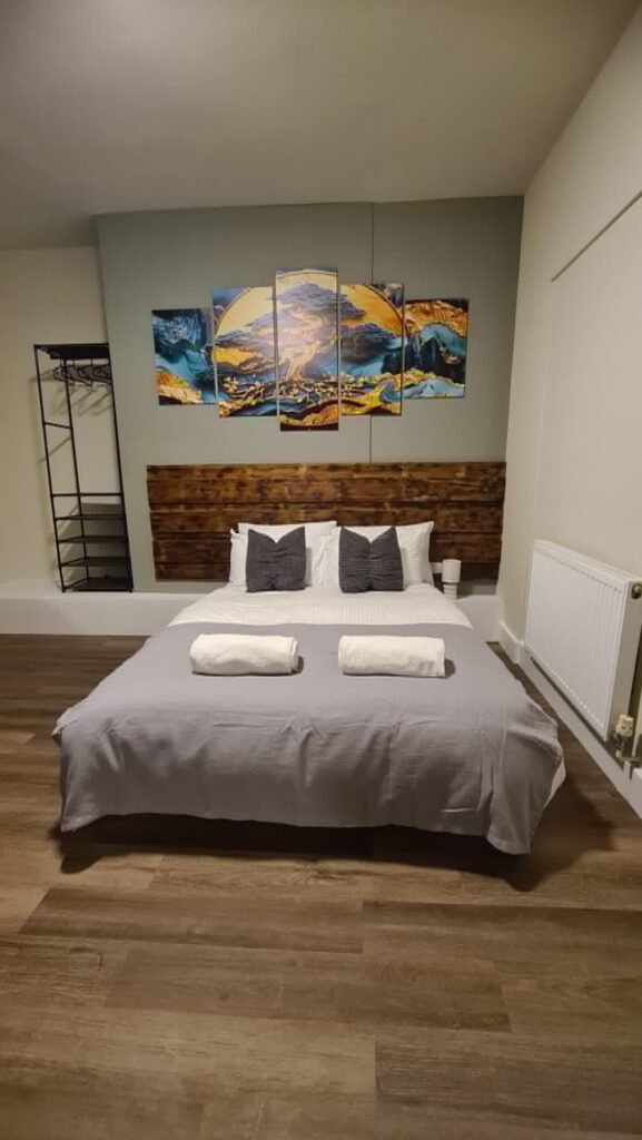 Hotel bed with wooden rustic headboard and stylish artwork wall art above the bed